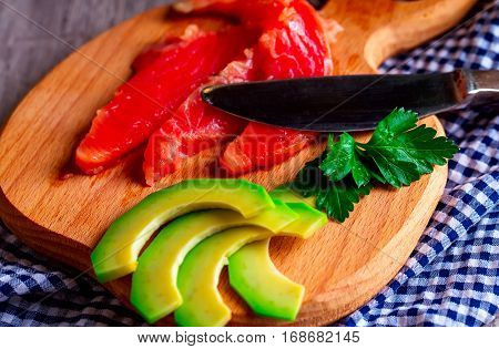 Sliced avocado and salmon on a wooden Board.Knife. Blue napkin