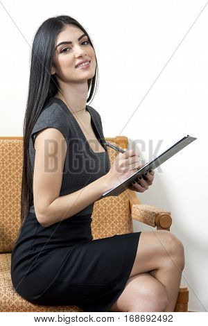 Young secretary is looking happy and smiling while taking notes.