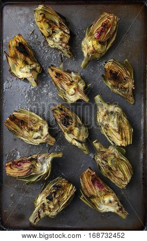 High angle view of grilled artichoke halves on a baking sheet.