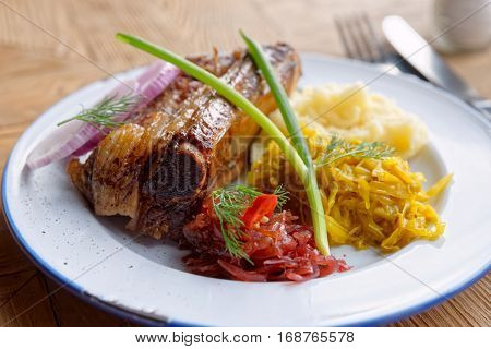 Grilled pork ribs with sauerkraut and mash potatoes on restaurant table - hearty dish