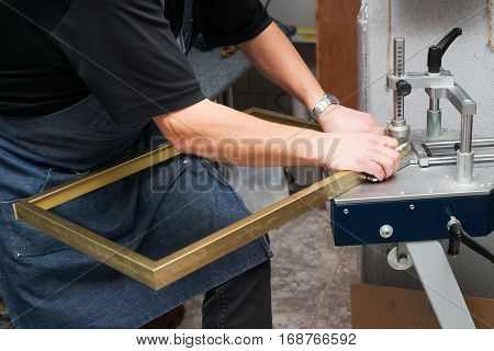 Craftsman working on frame in frameshop. Professional framer hand holding frame angle. Top view.