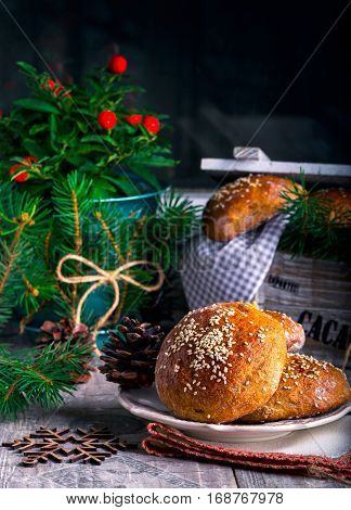 Fresh buns with sesame seeds on a plate. Whole-grain bread. The pine cones. Wooden snowflakes