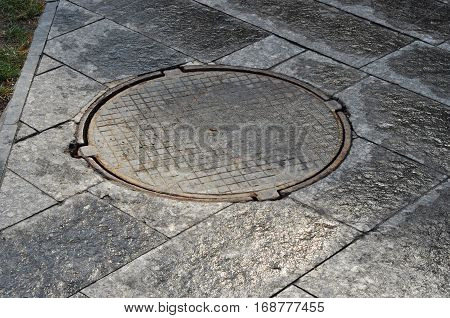 Close up on manhole cover on garden pavement