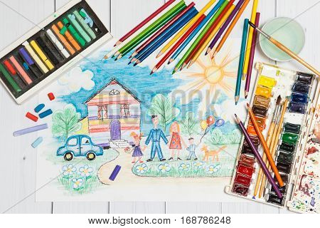 Hand drawn Bright Childrens Sketch With Happy Family, House, Dog, Car on the Lawn with Flowers with lying flat pencils, paints and pastel - concept of children creativity, close up top view