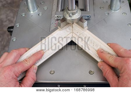 Craftsman working on frame in frameshop. Professional framer hand holding frame angle. Top view.
