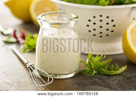 Homemade lemon ranch dressing in a small jar with fresh greens