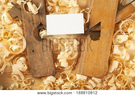 Blank business card on wooden table for carpenter tools with sawdust.Copy space. Top view.