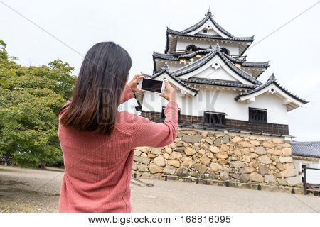 Woman taking photo with mobile phone on Hikone castle