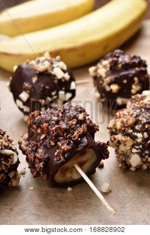 Summer dessert snack frozen banana covered with chocolate and peanuts