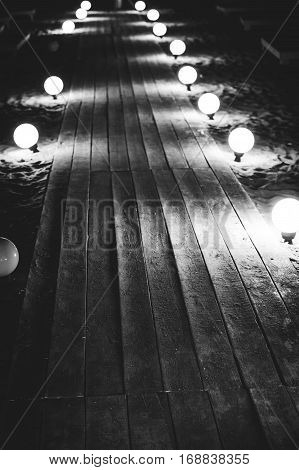Wooden platform on the beach lit by lanterns.