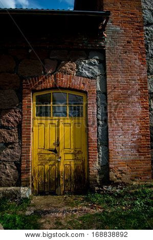 Yellow door in old stone building on a sunny day.