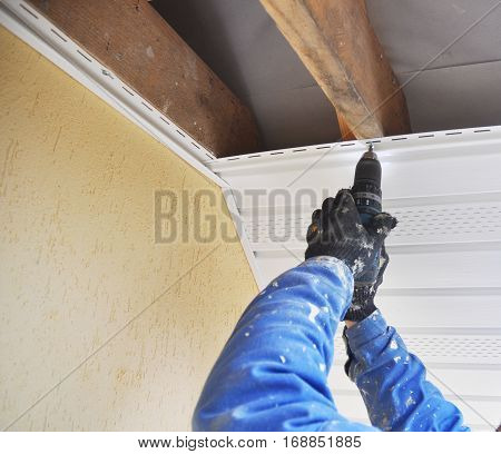 Constructor Install Soffit. Roofing Construction. Soffit and Fascia is Usually Constructed of Vinyl Wood or Aluminum and is Installed on the Underside of Roof Overhangs and Eaves
