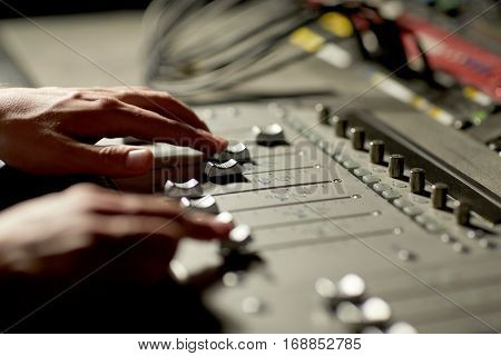 music, technology, people and equipment concept - hands using mixing console in sound recording studio