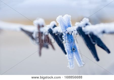 Frozen colorful clothes-pins on a rope at winter morning