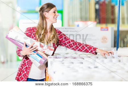 Young woman buying wallpapers in home improvement store