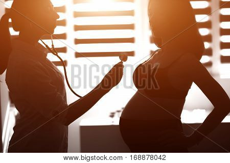 Silhouette Female Medicine Doctor Holding Stethoscope To Pregnant Woman Standing For Encouragement,