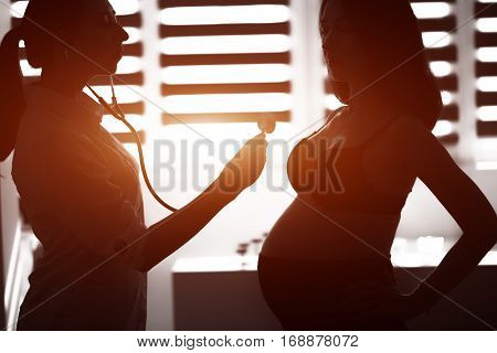 Silhouette Female Medicine Doctor Holding Stethoscope To Pregnant Woman Standing For Encouragement,