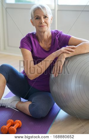 Senior woman sitting by fitness ball