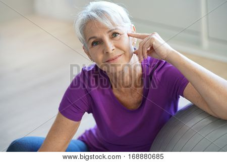Senior woman sitting by fitness ball