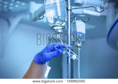 Doctor's hand and infusion drip in hospital on blurred background