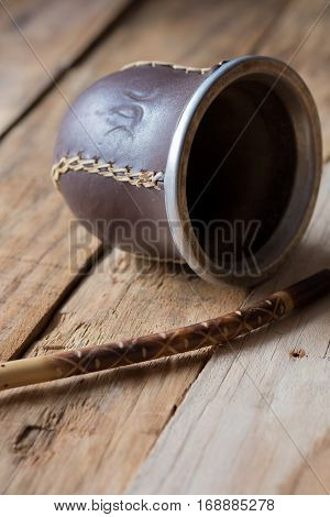Calabash gourd with bombilla straw for yerba mate on wood surface in rustic style