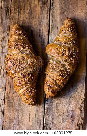 Whole wheat croissants with sesame seeds on rustic wood table top view, flat lay