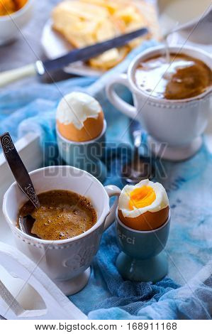 Breakfast for two. Strong coffee and 2 eggs hard boiled. Eggs and coffee are located on the white wooden tray.