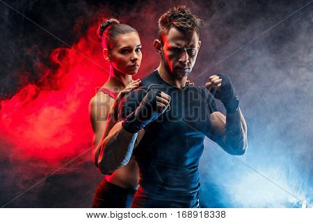 Strong boxer in stance with handwraps on his fists. With girlfriend standing behind him.