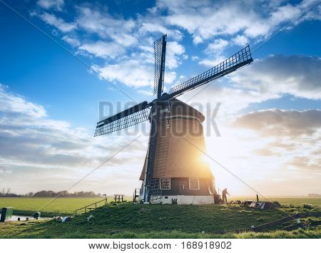 Windmill And Silhouette Of A Man At Sunrise In Netherlands