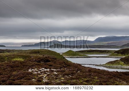 North Coast, Scotland - June 6, 2012: Irregularly shaped gray-water Loch Eriboll under dark cloudy skies. Wide shot showing land tongues background mountains and green and brown vegetation.