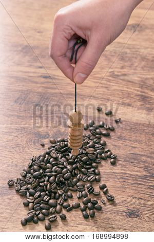 Hand with pendulum dowsing over coffee beans to check its quality