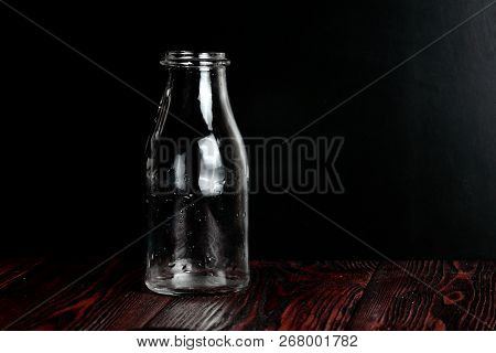 Bottle Of Milk On A Black Background And Wooden Table