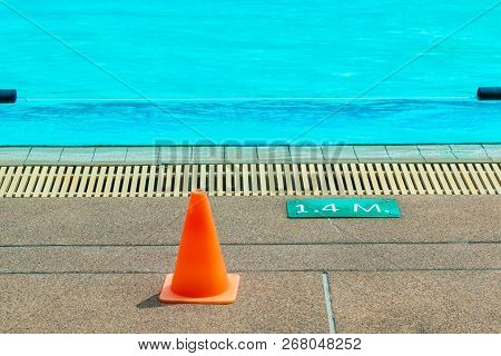 1.4 Meter Depth Sign And Small Plastic Orange Cone At An Outdoor Swimming Pool