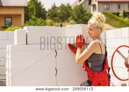 Strong Pretty Woman Working On Construction Site, Building House, Installing Gray Airbricks. Industr