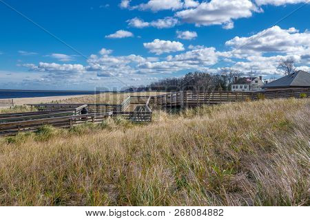 A Wooden Walkway Over The Sand Dunes At Bayshore Waterfront Park In New Jersey.
