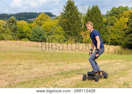 Young Caucasian Man Rides Electrical Mountainboard Off Road In Nature
