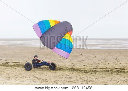 Caucasian Male Teen Drivesg Kite Buggy With Kite Flyer On Beach With Sea
