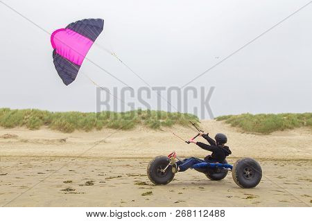 Dutch Teenage Boy Driving Kite Buggy With Kite Flyer On Beach