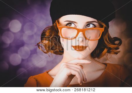 Portrait Of A Beautiful Girl With Curly Hair Dressed In A Beret And Glasses Against A Gray Backgroun