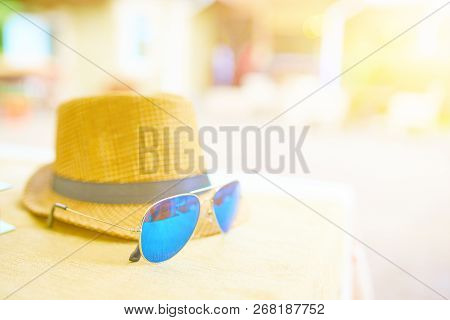 Straw Hat And Blue Sunglasses On A Hot Day Off On The Table. Vacation Concept