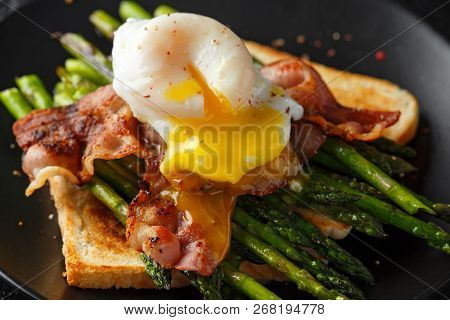 Benedict Poached Duck Egg With Crispy Bacon And Fried Asparagus On Toasts For Breakfast