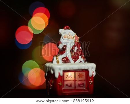 Santa Claus Statuette Doing An Exercise Waiting For Christmas. Colored Bokeh