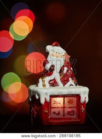 Santa Claus Statuette Doing An Exercise Waiting For Christmas. Colored Bokeh