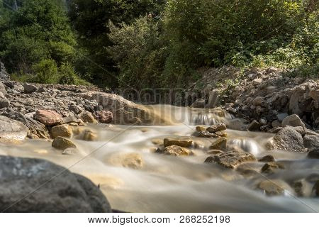 Mountain River With Rapid Stream And With Bright Blurred Waves. Big Mossy Boulders In Clear Water.