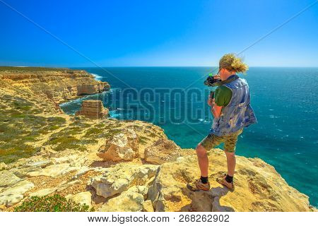 Travel Photographer With Stabilizer Takes Shot Of Island Rock In Kalbarri National Park, Western Aus