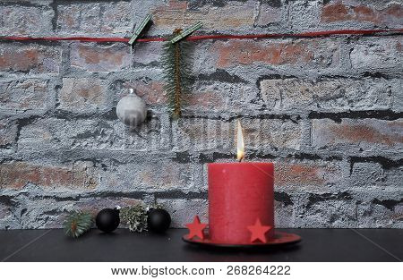 Colorful And Crisp Image Of Burning Candle And Christmas Decoration In Front Of Brick Wall