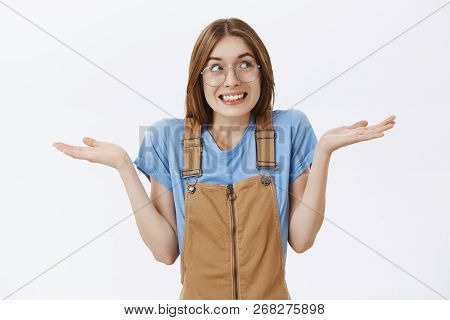 Waist-up Shot Of Cute Silly European Female Shrugging Looking Right With Sorry Smile Spreading Hands