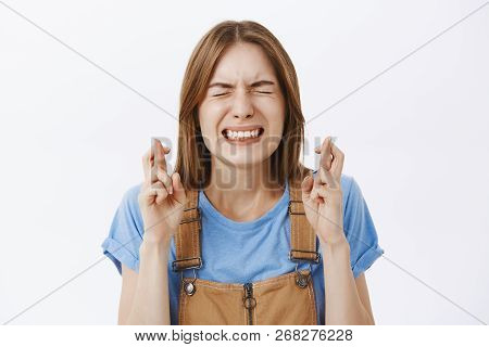 Close-up Shot Of Woman Eager For Dream Come True Praying Intense With Closed Eyes And Clenched Teeth