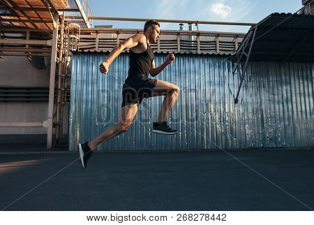 Handsome Young Man Running In Ndustrial Building Background.  Runner, Jogger, Fitness Activity