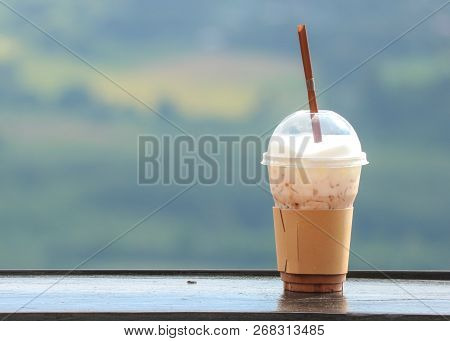 An Iced Coffee In Plastic Cup With Natual View As Background.